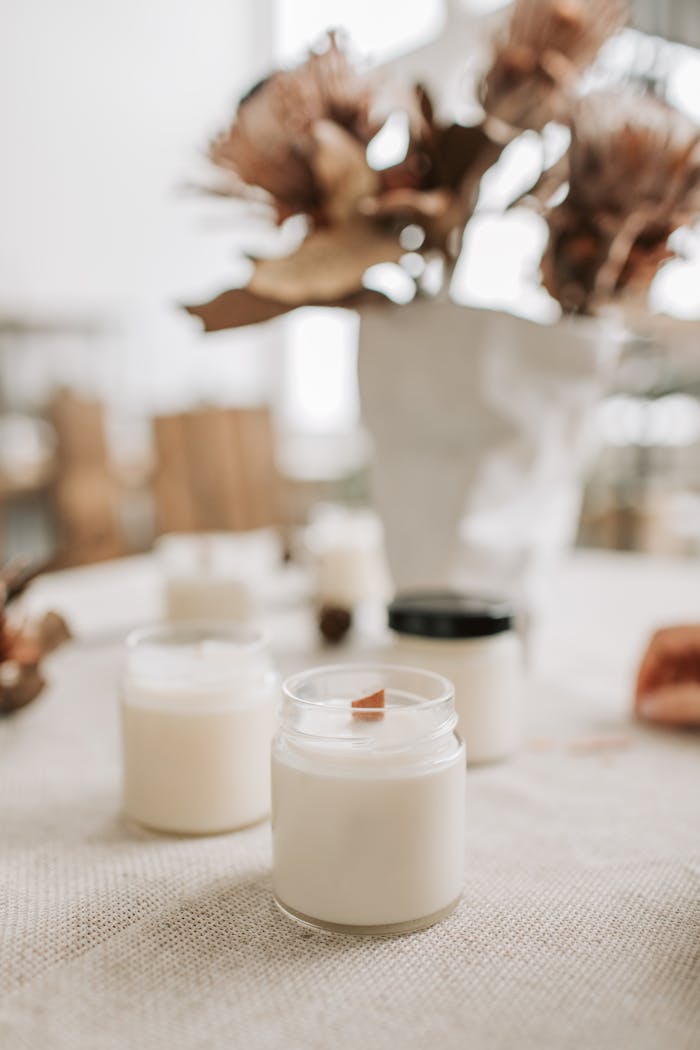 Close-up of handmade candles with wooden wicks in glass jars, showcasing artisan quality.